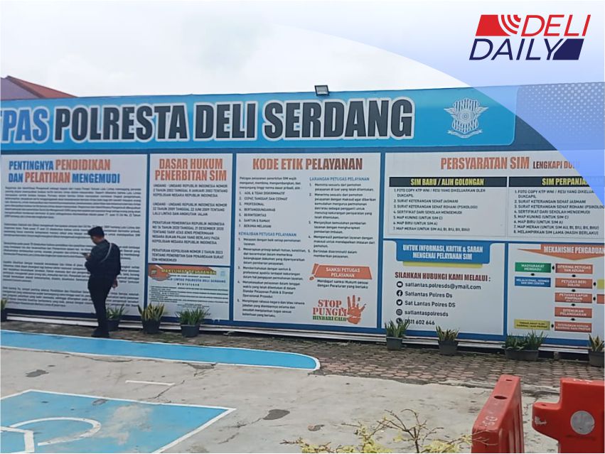 Seseorang berdiri didepan papan informasi syarat pembuatan SIM di Deli Serdang